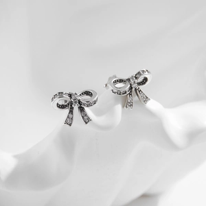 Elegant S925 sterling silver bow knot stud earrings with sparkling zircon on a white pedestal