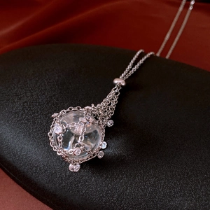 Close-up of a silver mesh sphere pendant with zircon crystals on dark red silk