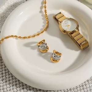 Vista piatta di orologio d'oro, orecchini misti e collana su vassoio di ceramica