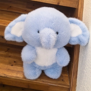 Cute light blue stuffed elephant toy with soft fluffy fur on a wooden staircase