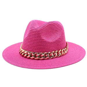 Detailed texture of fuchsia woven fedora hat featuring a chunky gold chain strap accent