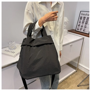 Detail of a large black nylon tote bag with wide strap on a model for daily use