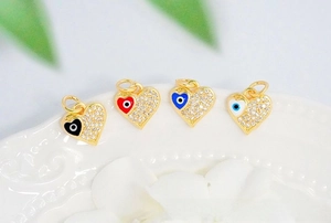 Macro shot of 18K gold plated heart charms with zircon inlay and evil eye enamel patterns