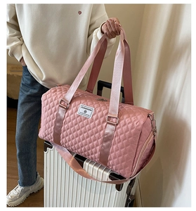 Gros plan du sac de voyage matelassé rose avec étiquette ZUOMANNI sur valise