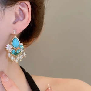 Detail of ethnic turquoise earrings with pearl tassels and crystal accents on a model
