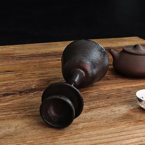 Cáliz de gres vintage con brillo metálico sobre superficie de madera rústica