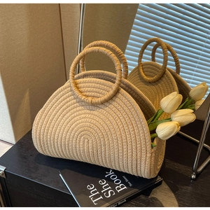 Detail of a large woven straw beach bag with round handles and white tulips inside