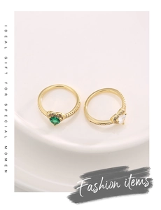 Detailed view of gold rings featuring heart-shaped green and clear zircon stones