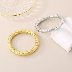 Detailed close-up of gold and silver stainless steel bangles with geometric diamond patterns