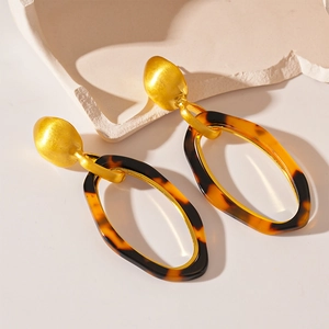 Close-up of vintage resin tortoise shell oval hoop earrings with matte gold metal finish