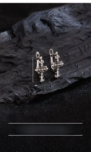 Close-up of vintage silver cross earrings with iris motif on rustic charcoal background