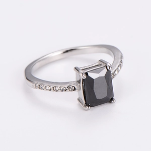 Macro view of silver ring featuring a rectangular black gem and side pave diamonds