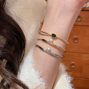 Vue détaillée de bracelets plaqués or 18k avec perles et une pierre ovale verte