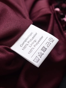 Close-up of white care label with washing instructions on dark burgundy sequin dress