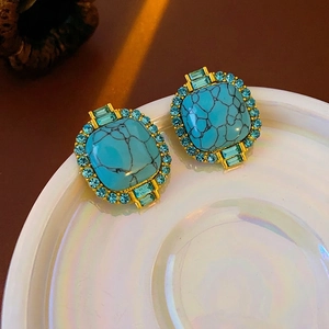 Vintage gold square earrings with turquoise stone and blue diamonds on a white tray