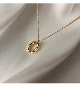 Detail of gold oval donut pendant with hammered texture on a white satin background