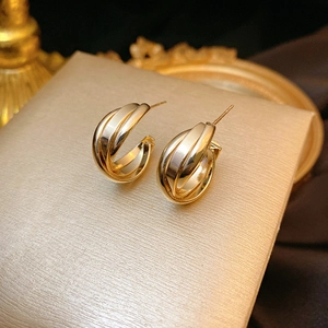 Macro shot of gold-plated triple interlaced hoop earrings on silk fabric background