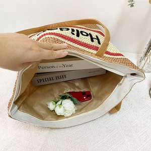 Interior view showing large capacity straw tote bag with zipper pocket and holiday embroidery