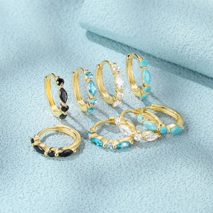 Detail of gold huggie earrings set with marquise and round cut colorful gemstones