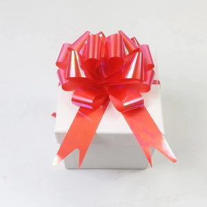 Close-up of a vibrant red laser film pull bow on a white gift box for packaging decoration