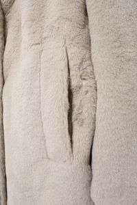 Detail of side pocket on warm faux fur coat showing soft plush texture and stitching