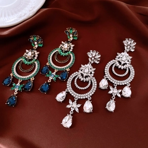 Détails de boucles d'oreilles baroques avec pampilles et cristaux sur soie marron
