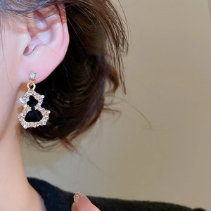 Detail of a gold gourd-shaped earring with pink and white crystals on a model's ear