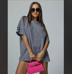Detail of distressed grey oversized t-shirt featuring ripped hem and raw shoulder seams