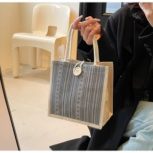 Detail of striped linen tote bag with rope handle and large decorative button