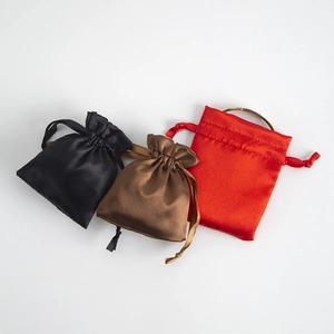 Detail of satin drawstring gift pouches in black, brown and red with smooth texture