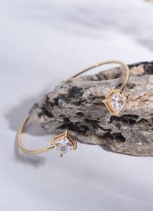Close-up of golden adjustable open cuff bracelet with square zircon on stone