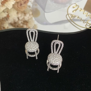 Macro shot of silver chair earrings with pavé cubic zirconia on black velvet background