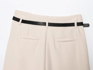 Detailed view of beige trousers featuring a black leather belt and waist stitching