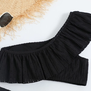 Close-up of black ruffled bikini top with pointelle texture and beach accessories
