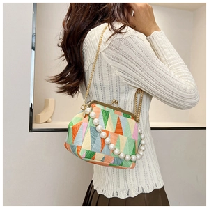 Detail of geometric patchwork shell bag with faux pearl handle and gold chain strap