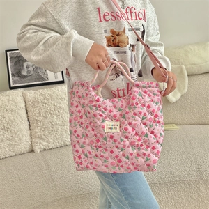 Detail of pink floral quilted handbag showing soft padded texture and woven logo tag