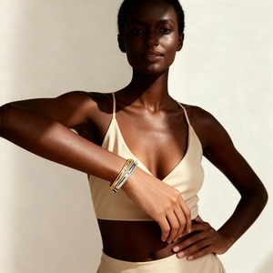 Detail of 18k gold plated T-shape hinge bangles on dark skin model with elegant shadows