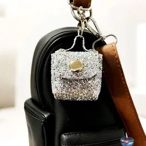 Close-up of silver sequin mini leather bag keychain with metal hook on black backpack
