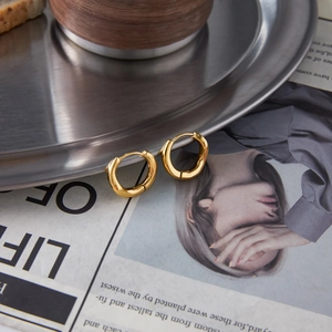 Detail of 18k gold plated stainless steel hoop earrings on a vintage metal tray
