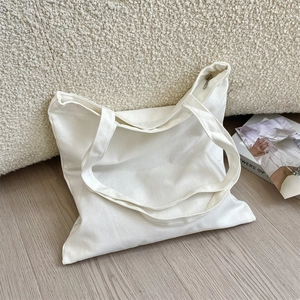 Close-up of white canvas tote bag with metal zipper on a cozy minimalist sofa