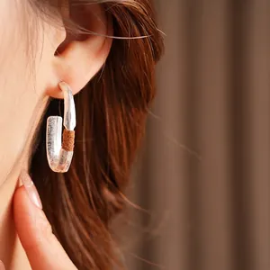 Minimalist matte oval hoop earrings with leather wrap detail worn by model