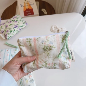Close-up of floral cotton pouch with green leaves and pink stripes held by hand