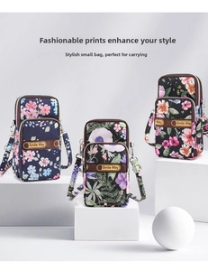 Detailed view of three mini floral printed shoulder bags with double zippers on white pedestals