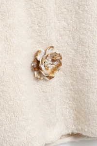 Détail d'un bouton fleur ambre avec perles sur un cardigan en polaire douce