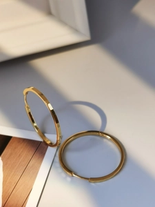 Detail of S925 sterling silver stamp on minimalist gold circular hoop earrings