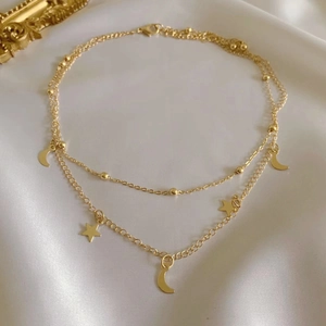 Gold double-layer stainless steel anklet with moon and star pendants on silk background