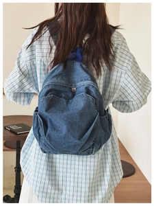 Lifestyle view of a vintage blue denim backpack with front pocket worn by a woman