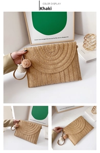 Detail view of khaki straw woven clutch bag with decorative pompom and envelope design