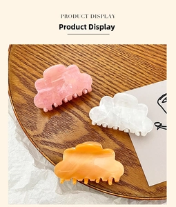 Three medium cloud-shaped acrylic hair claws in pink white and orange on wood tray