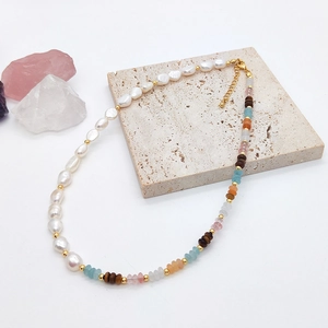 Detailed close-up of Baroque pearl necklace with natural gemstones on stone base